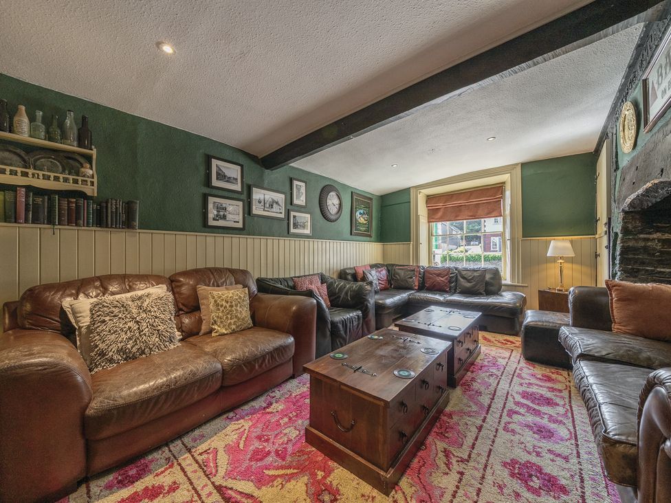 A lounge with leather sofas wooden coffee tables books and framed pictures on walls at The Boars Head Pub in Bishops Castle