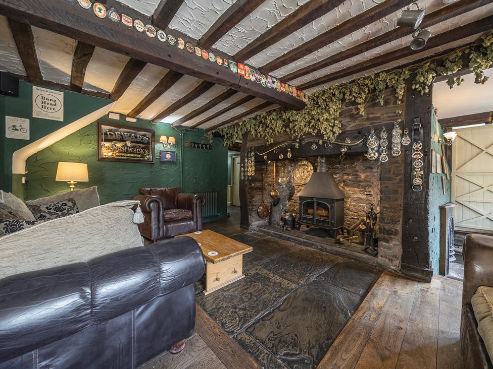 A sitting area with leather armchairs a stone fireplace and wooden beams on the ceiling at The Boars Head Pub in Bishop's Castle