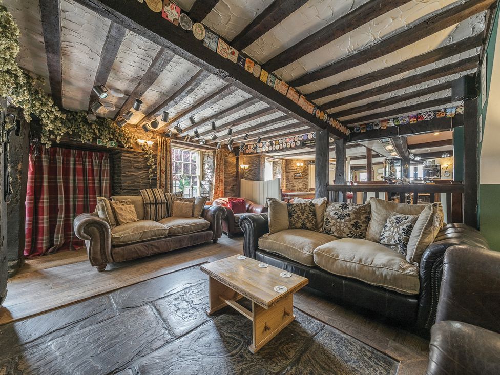 A pub lounge with sofas stone floor wooden coffee table and timber beam ceiling at The Boars Head Pub Bishop's Castle