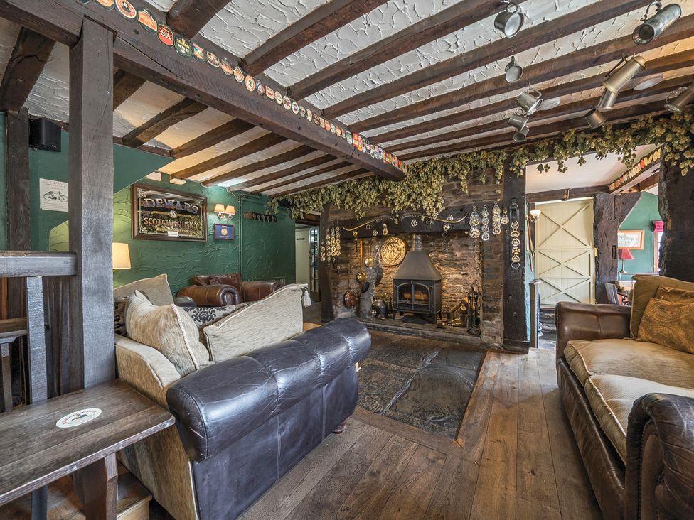 A pub interior with sofas a fireplace wooden beams and beer mats at The Boars Head Pub in Bishops Castle