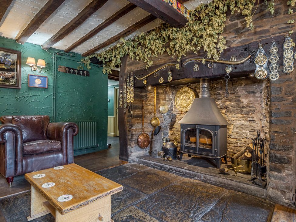 A room with a stone fireplace wood stove armchair and wooden table at The Boars Head Pub in Bishops Castle