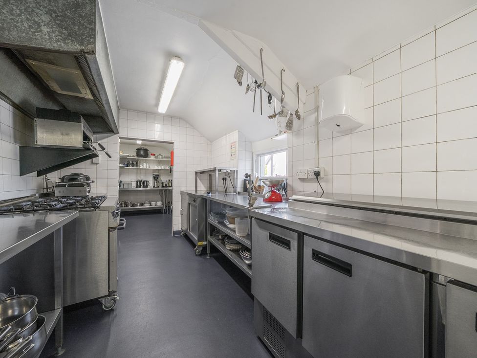 A commercial kitchen with stainless steel counters stove and shelves with kitchenware at The Boars Head Pub in Bishops Castle