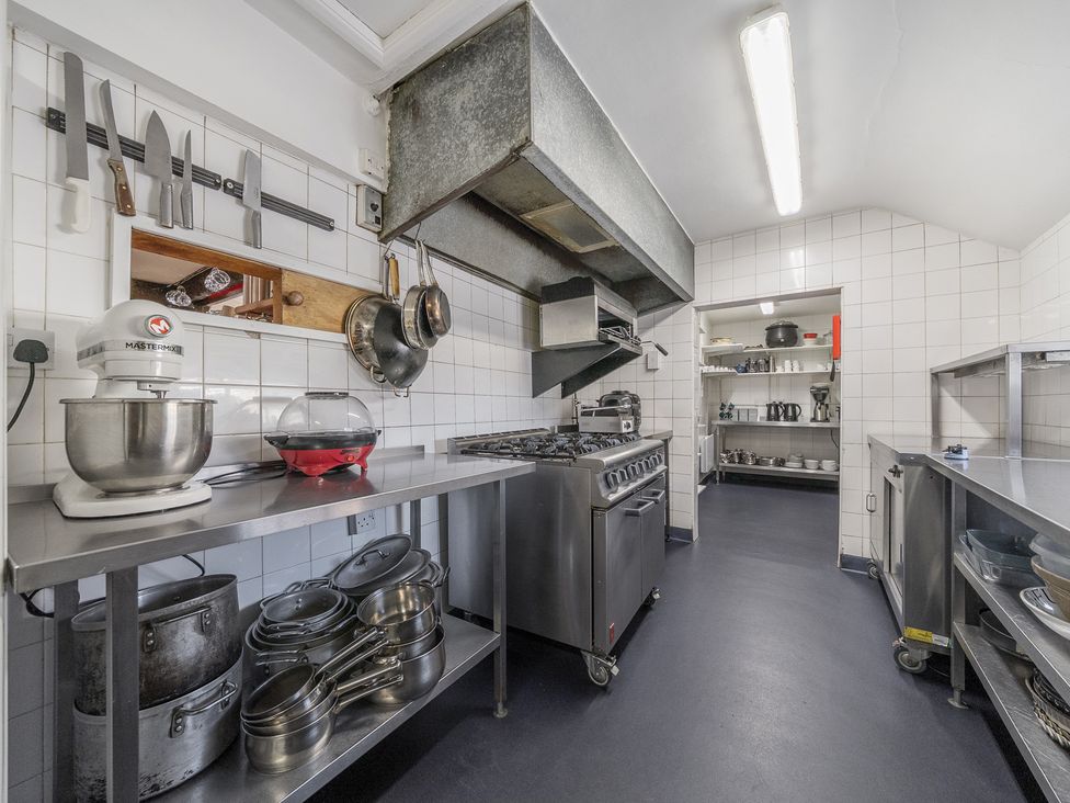 A commercial kitchen with stainless steel counters pots pans knives and a stove at The Boars Head Pub in Bishops Castle