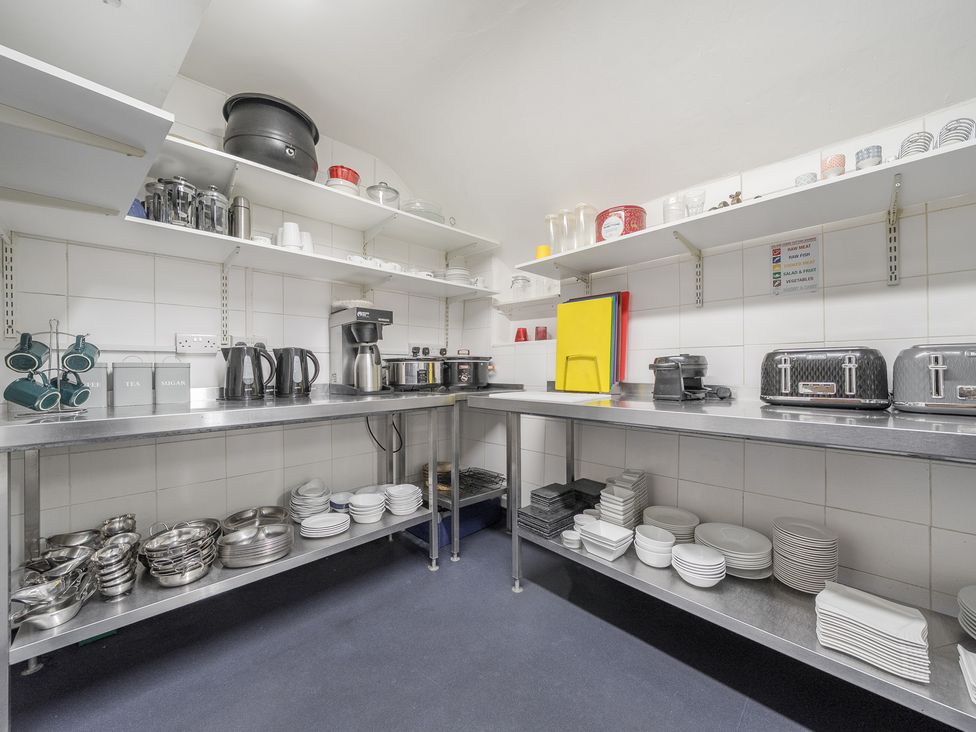 A kitchen with stainless steel shelves and counters holding kettles crockery toasters and cutting boards at The Boars Head Pub in Bishop's Castle