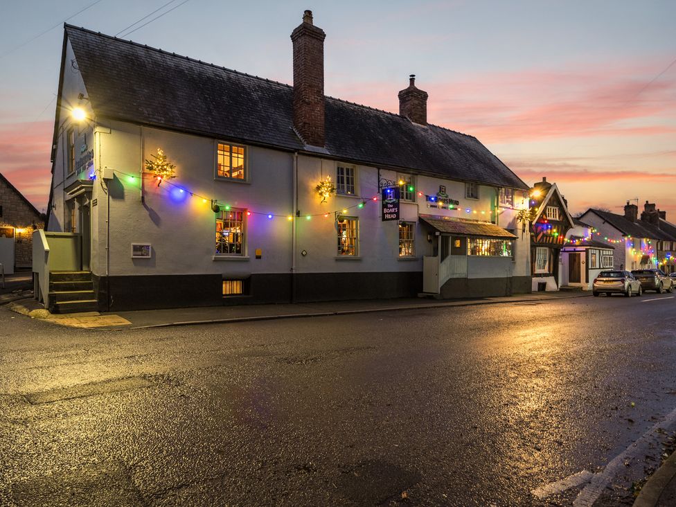 A pub with colorful lights and cars on the street at The Boars Head Pub in Bishop's Castle