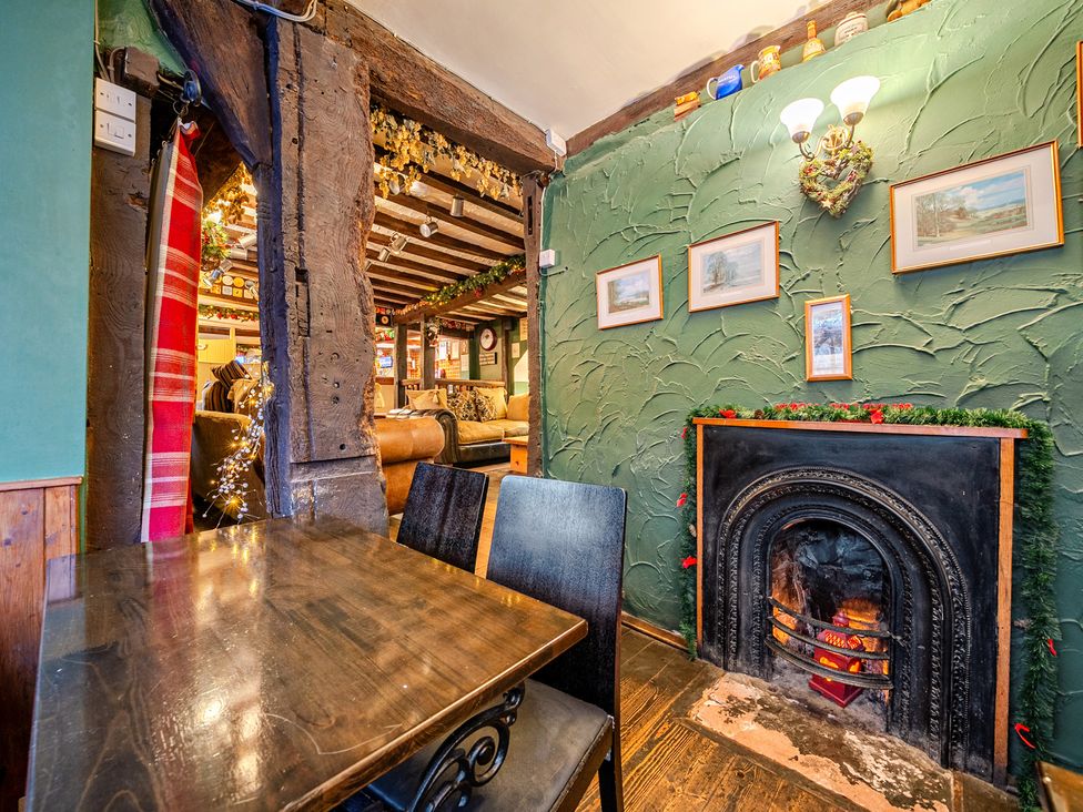 A dining room with a fireplace and wooden table at The Boars Head Pub in Bishop's Castle