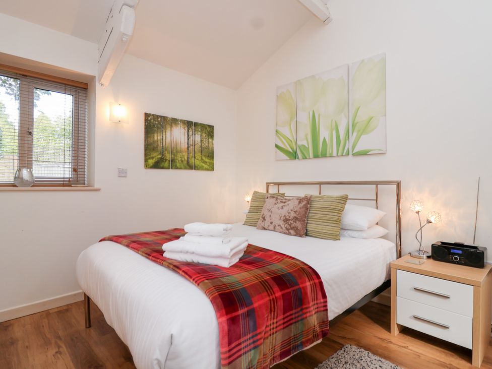 A bedroom with a bed and bedside table at Tregona in Buckland Monachorum near Yelverton