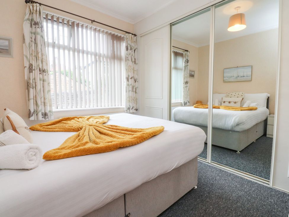 A bedroom with a bed and mirror at Cosy Bee in Heysham