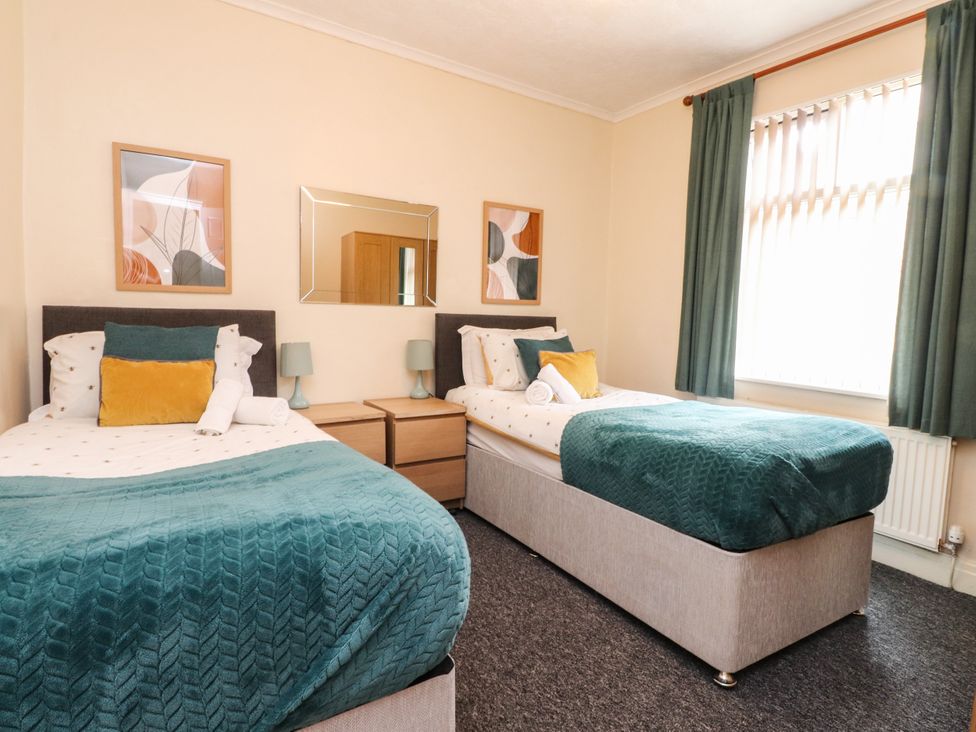 A bedroom with two beds and artwork on the wall at Cosy Bee in Heysham
