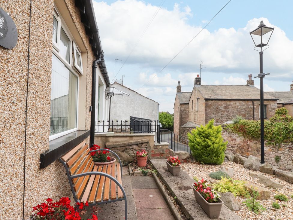 A garden with a bench and potted plants at Cosy Bee in Heysham