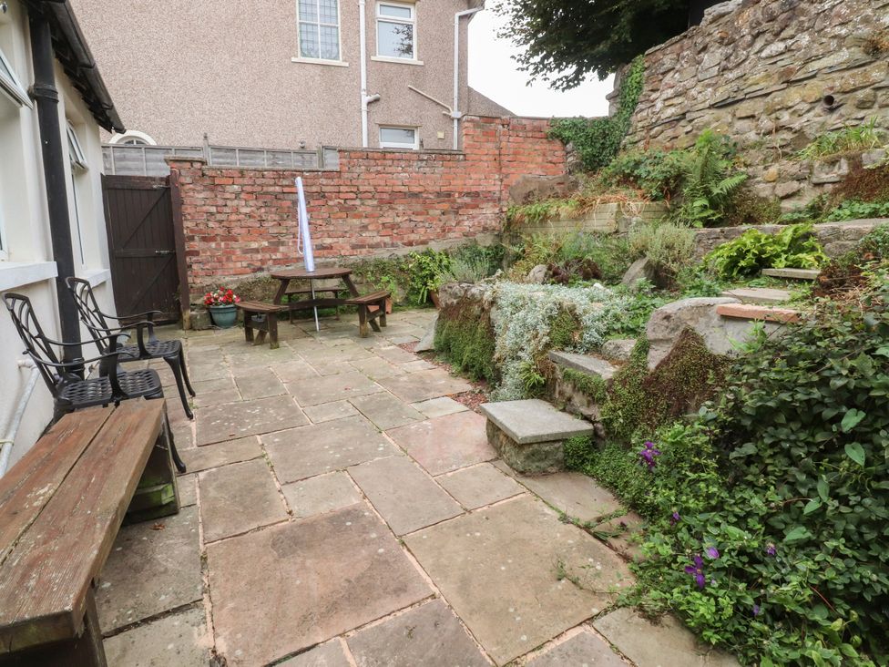A garden with a table and chairs near a stone wall at Cosy Bee in Heysham