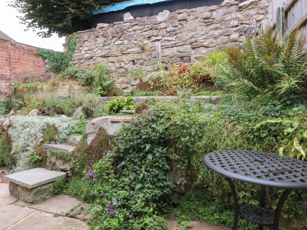A garden with stone walls and plants at Cosy Bee, Heysham