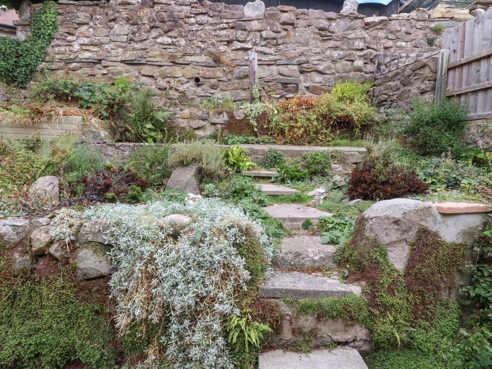 A garden with stone wall and steps at Cosy Bee Heysham