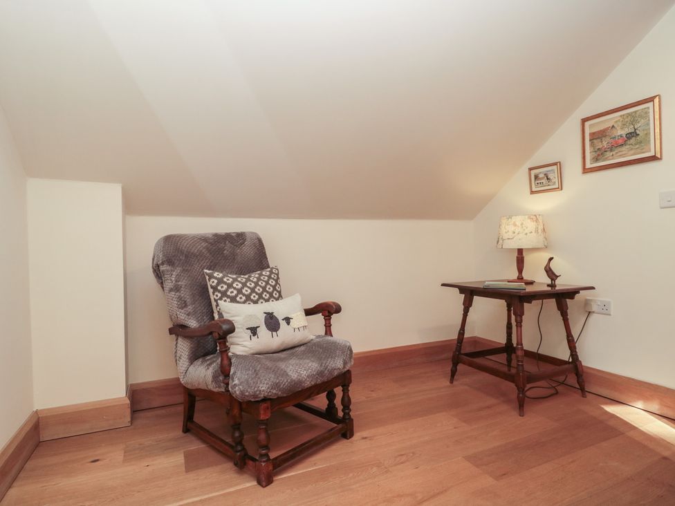 A snug with a rocking chair and a side table at Bramble Cottage in Somerton