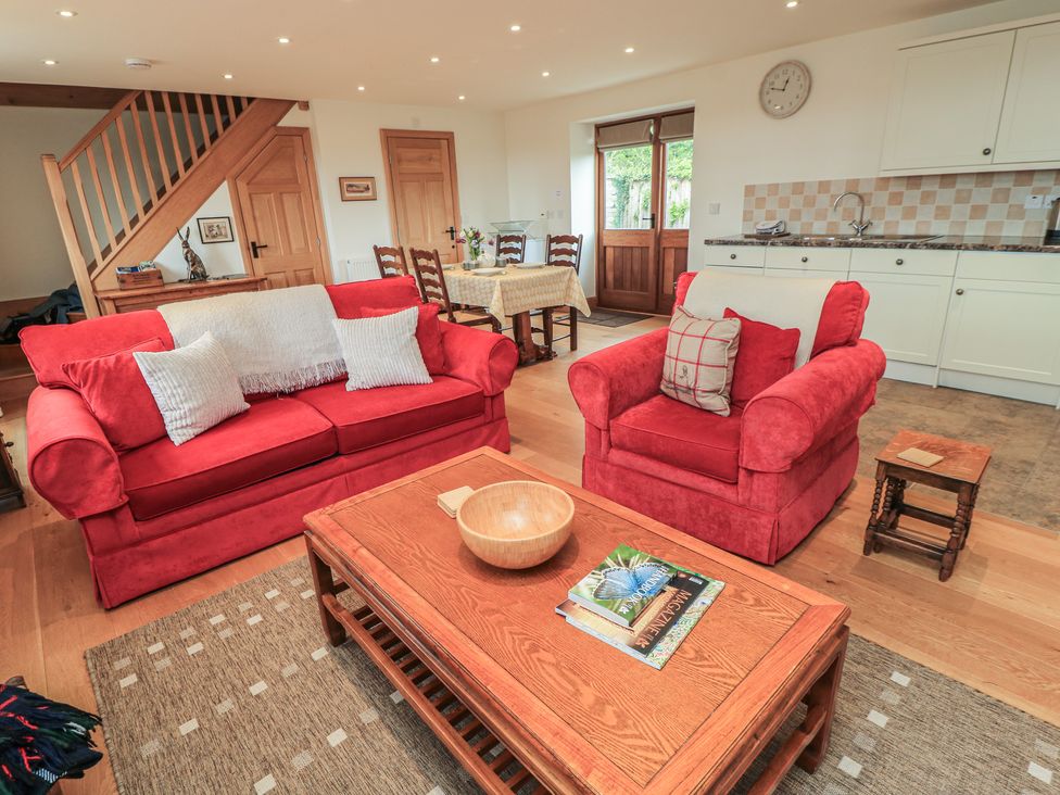 A living room with red furniture and a dining area at Bramble Cottage in Babcary near Lydford-On-Fosse