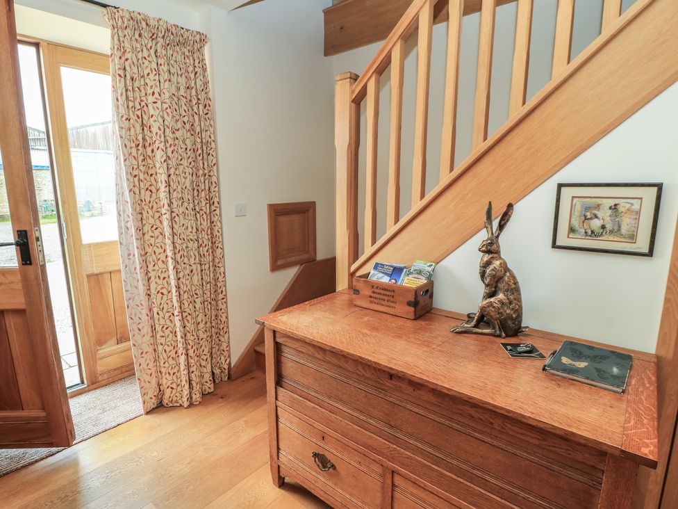 An entryway with a wooden table and staircase at Bramble Cottage in Babcary near Lydford-On-Fosse