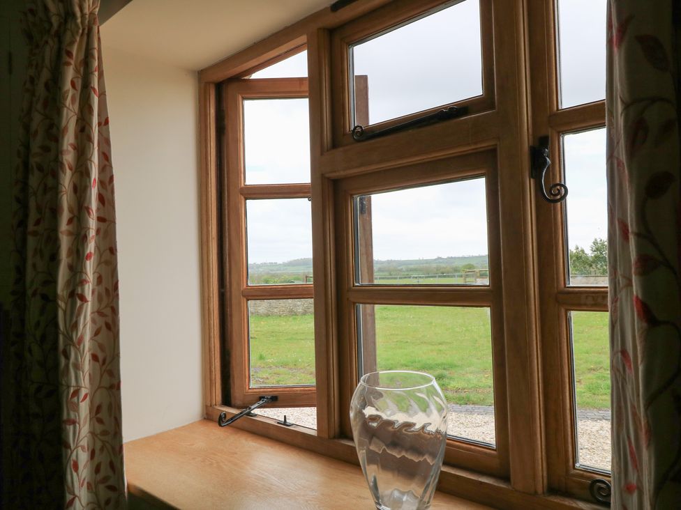 A window with wooden frames and a vase on the window sill at Bramble Cottage Babcary near Lydford-On-Fosse