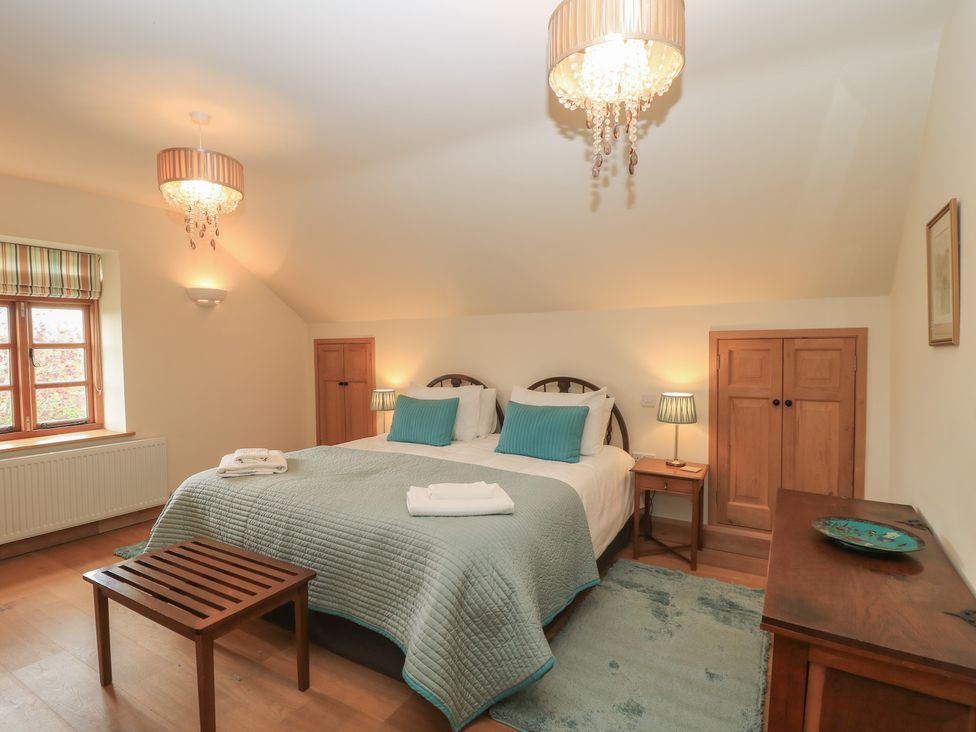 A bedroom with a large bed and wooden furniture at Bramble Cottage in Babcary near Lydford-On-Fosse