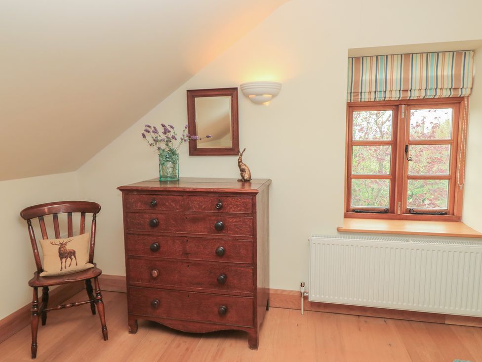 A bedroom with a dresser and a chair at Bramble Cottage in Babcary near Lydford-On-Fosse