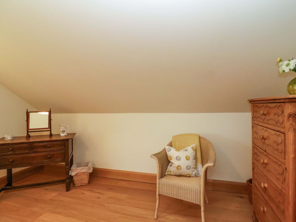 An attic space with a chair and desk at Badger Cottage in Lydford-On-Fosse