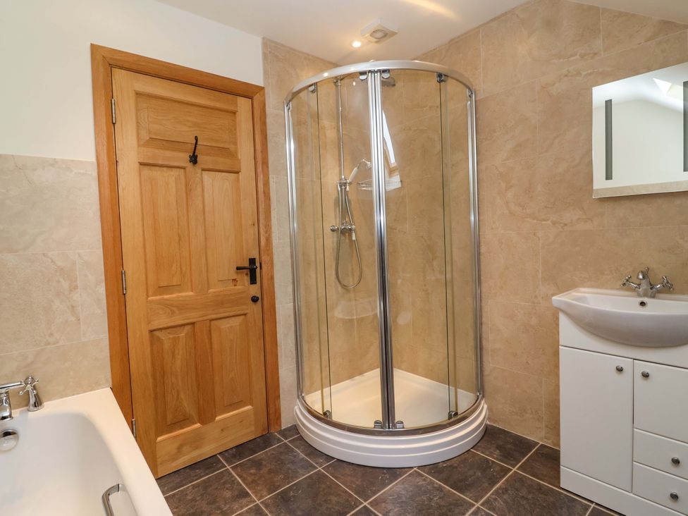 A bathroom with a shower, bathtub, and sink at Badger Cottage in Lydford-On-Fosse