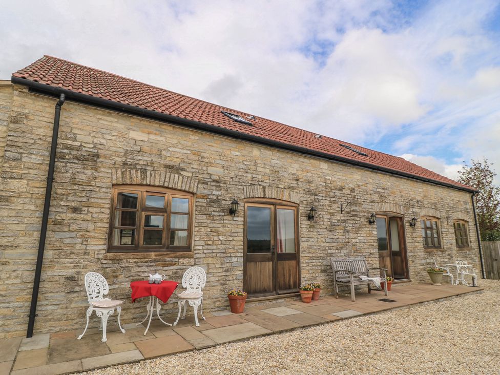 An outdoor patio with a table and chairs at Badger Cottage in Babcary near Lydford-On-Fosse