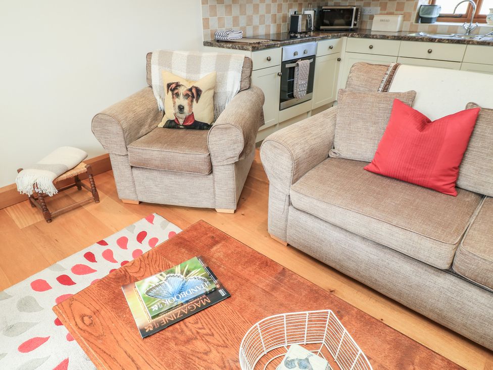 A living room with an armchair and sofa at Badger Cottage in Babcary near Lydford-On-Fosse