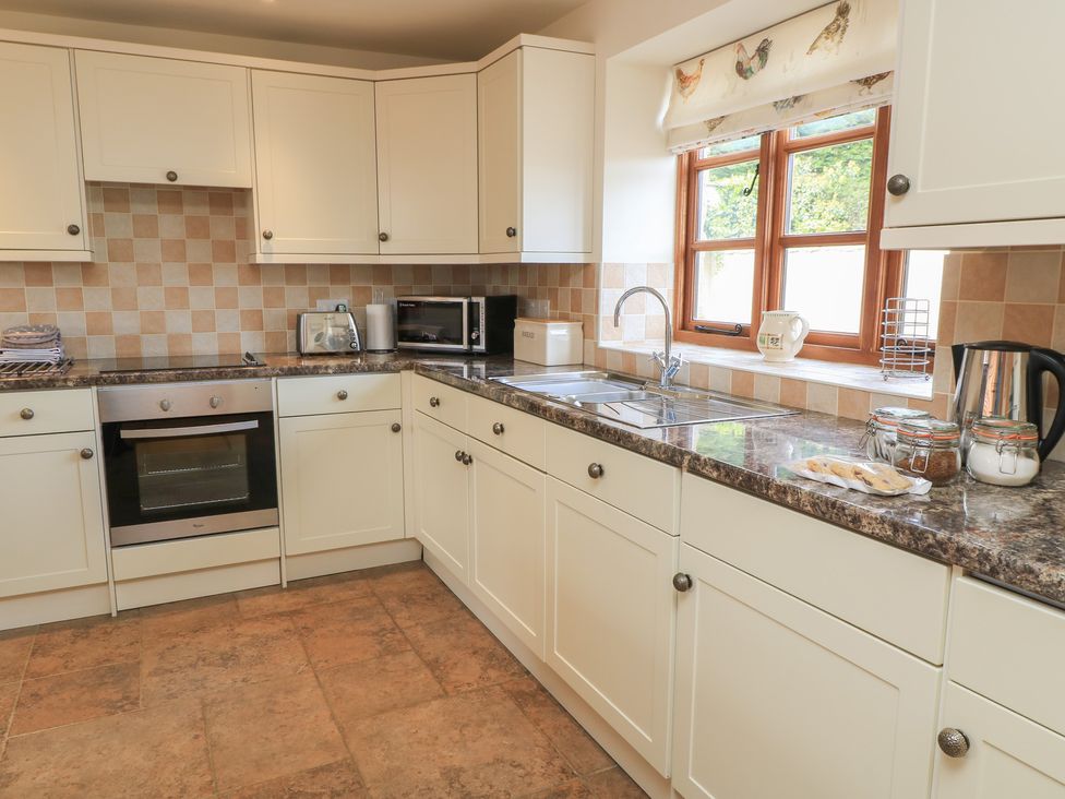 A kitchen with cabinets and appliances at Badger Cottage near Babcary