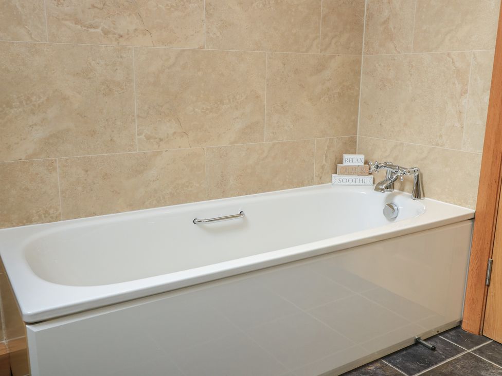 A bathtub with a faucet and decorative blocks at Badger Cottage Babcary near Lydford-On-Fosse