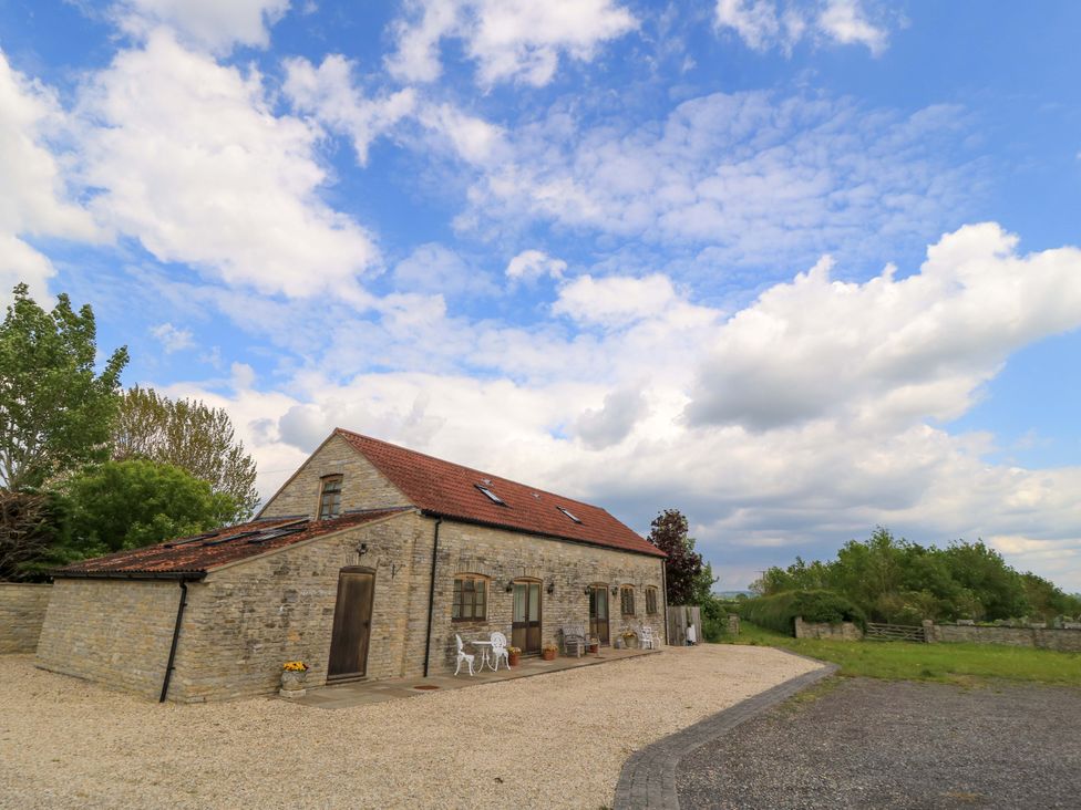 A cottage exterior with trees and a gravel area at Badger Cottage in Babcary near Lydford-On-Fosse