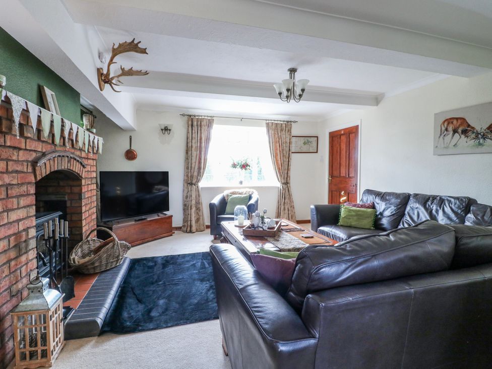 A living room with a fireplace and television at Fields Farm in Cheadle