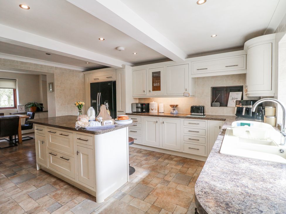 A kitchen with cabinets, an island, and appliances at Fields Farm in Cheadle