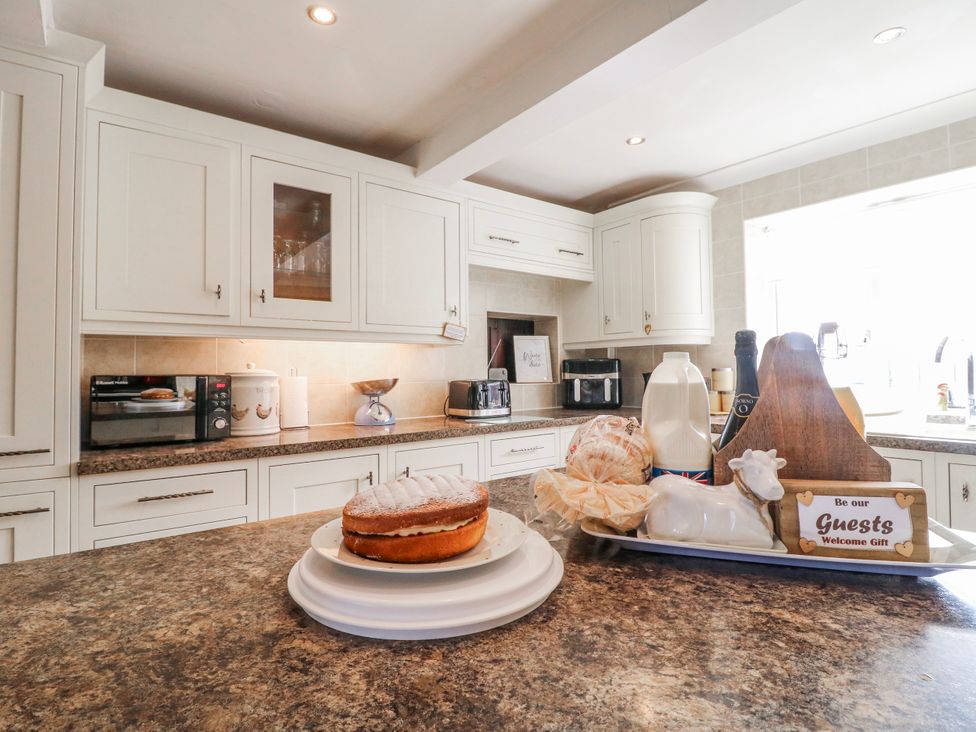 A kitchen with kitchen cabinets and a cake on the countertop at Fields Farm in Cheadle