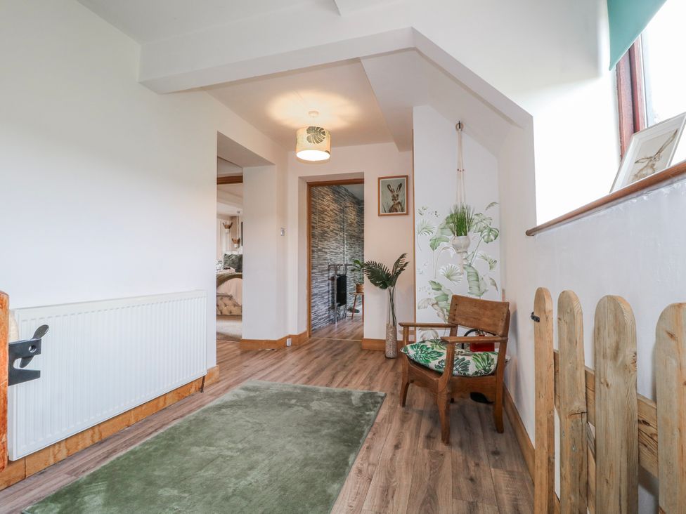 A hallway with a chair and wall art at Fields Farm in Cheadle