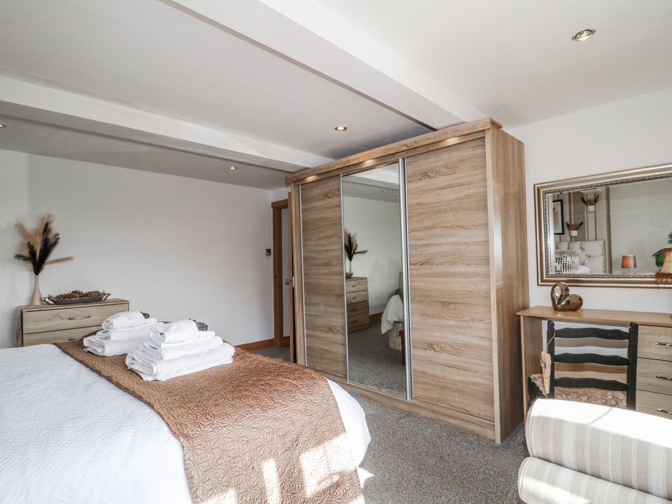 A bedroom with a bed, wardrobe, and desk at Fields Farm in Cheadle