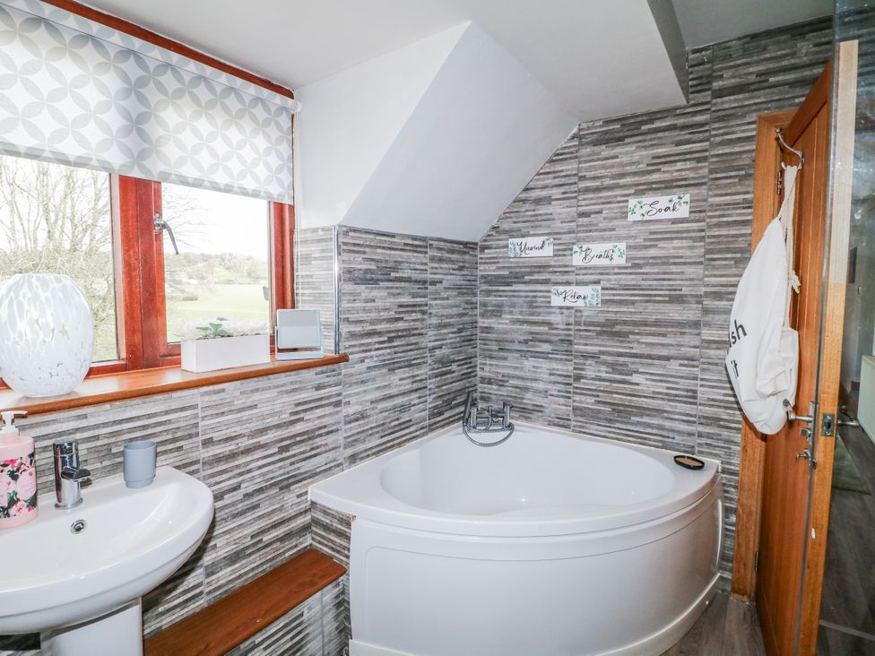 A bathroom with a bathtub and sink at Fields Farm in Cheadle
