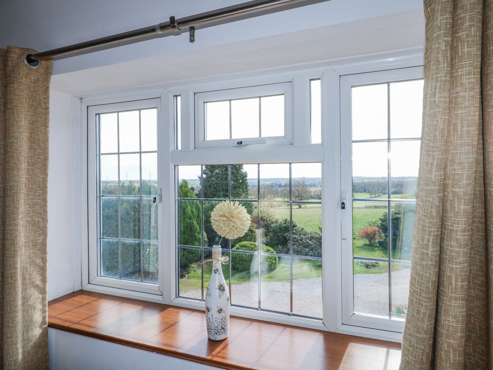 A living room window with a vase on a ledge at Fields Farm in Cheadle