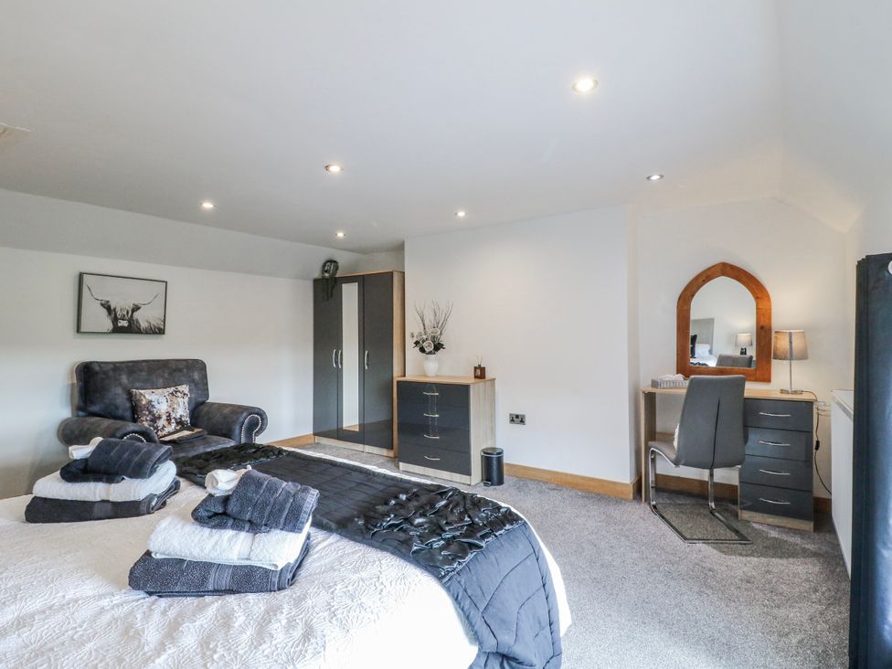 A bedroom with a bed, couch, wardrobe, and desk at Fields Farm in Cheadle