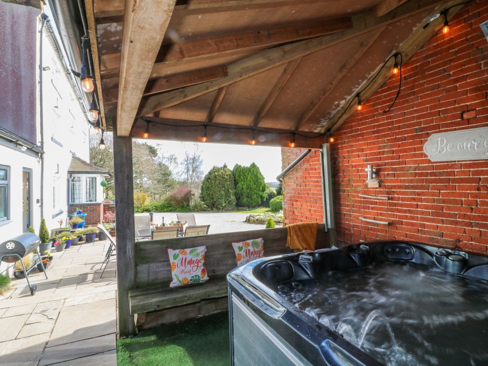 An outdoor area with a hot tub and wooden seating at Fields Farm in Cheadle