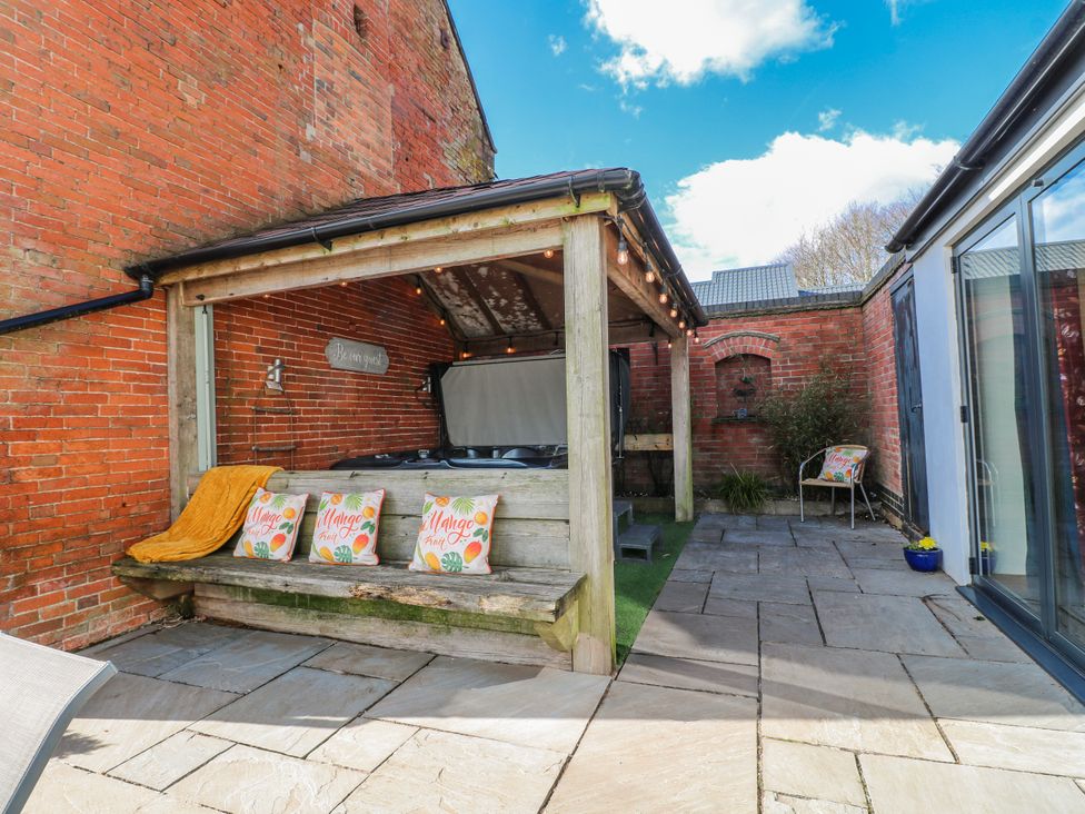 An outdoor space with a wooden shelter and hot tub at Fields Farm in Cheadle