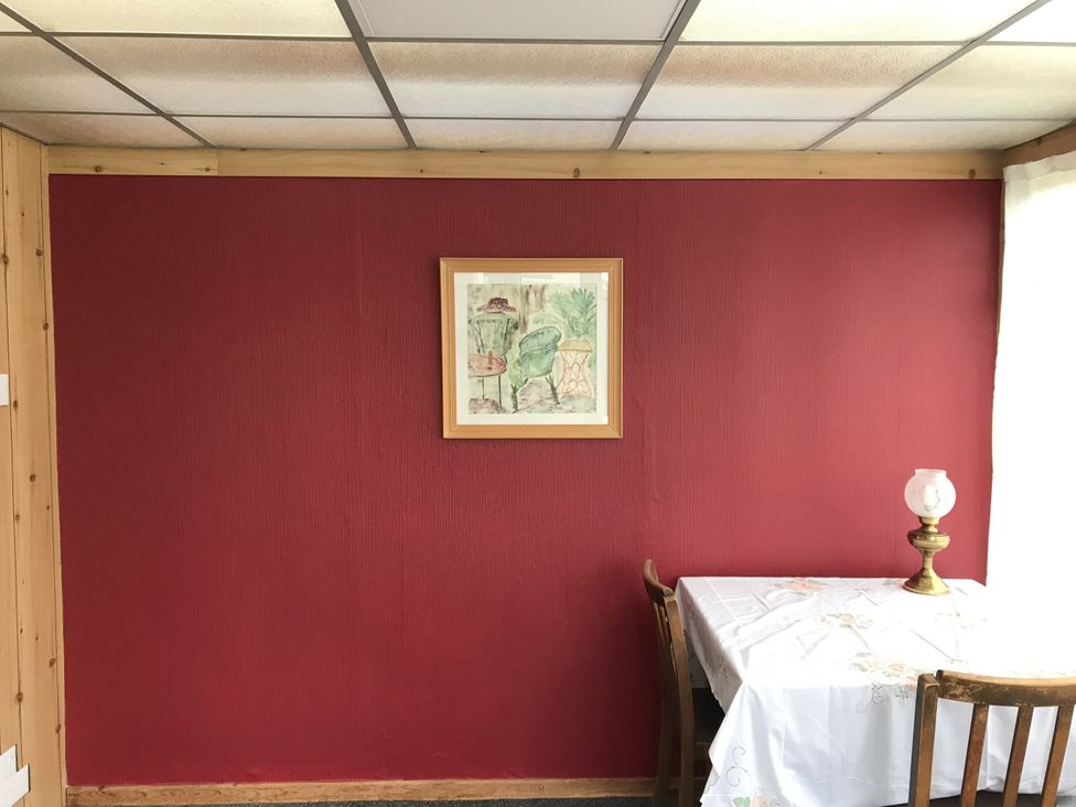A dining room with red wall, table, chairs, lamp, and framed painting at Lavender Harmony House Swindon