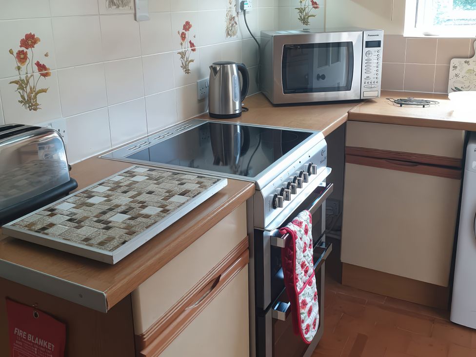 A kitchen with appliances including a kettle, microwave, and cooker at Lavender Harmony House in Swindon