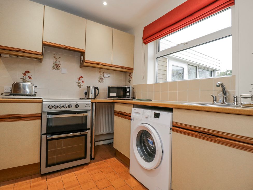 A kitchen with a cooker, washing machine and microwave at Lavender Harmony House in Swindon