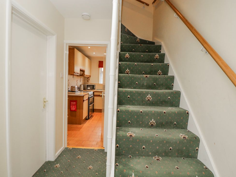 A hallway with a staircase and kitchen entrance at Lavender Harmony House in Swindon