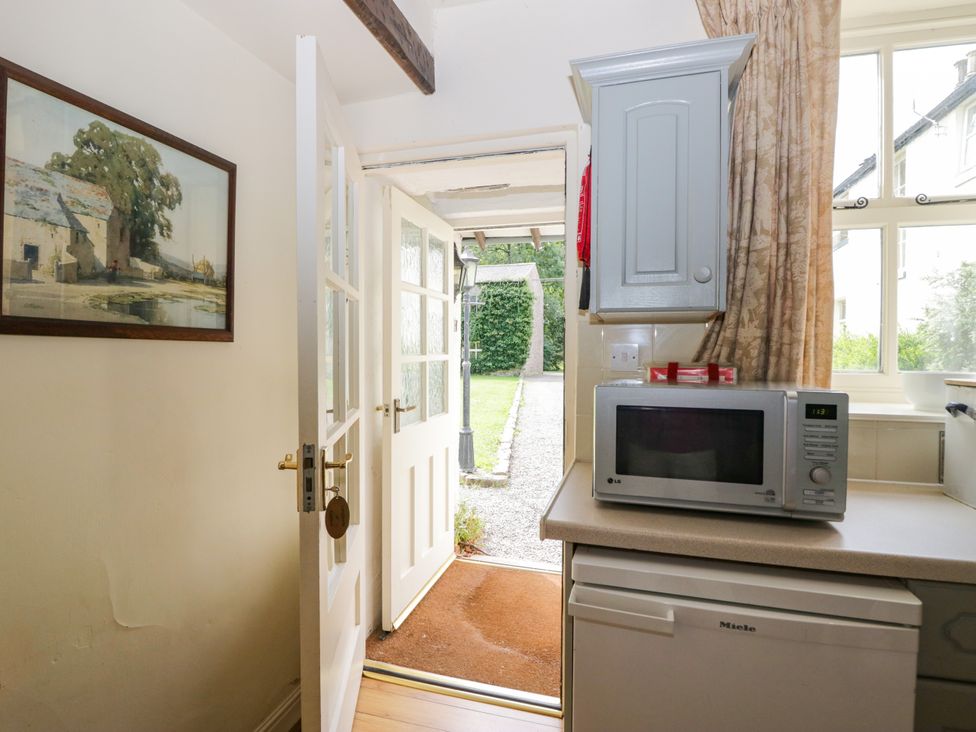 A kitchen with a microwave and an open door at Longlands Milkmaid's Parlour Cartmel near Grange-over-Sands