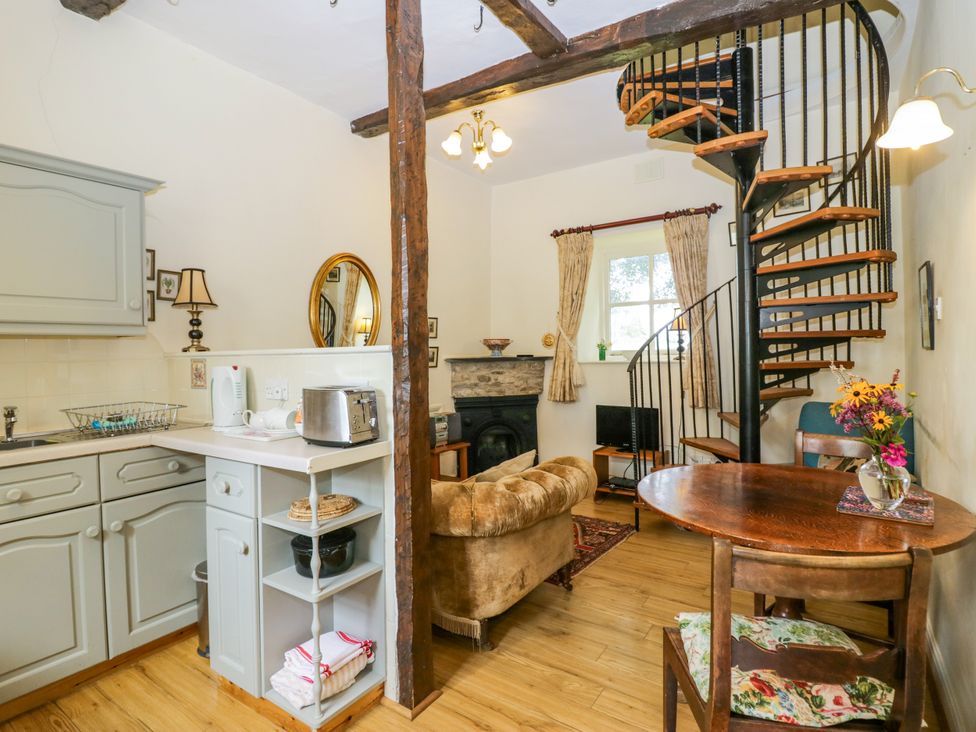 A living room with a sofa and spiral staircase at Longlands Milkmaid's Parlour Cartmel near Grange-over-Sands