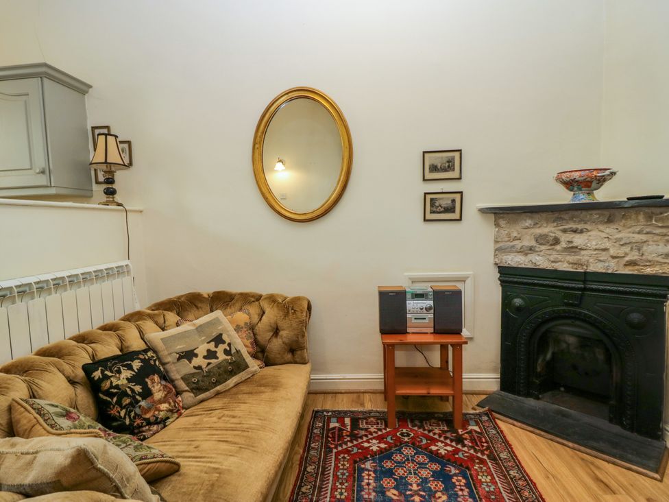 A living room with a sofa, lamp, and fireplace at Longlands Milkmaid's Parlour in Cartmel near Grange-over-Sands