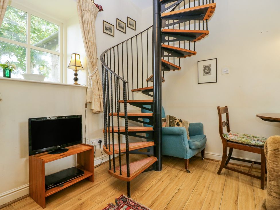 A living room with a spiral staircase and television at Longlands Milkmaid's Parlour Cartmel near Grange-over-Sands