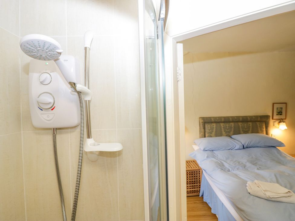 A shower unit and bed in a room at Longlands Milkmaid's Parlour in Cartmel near Grange-over-Sands