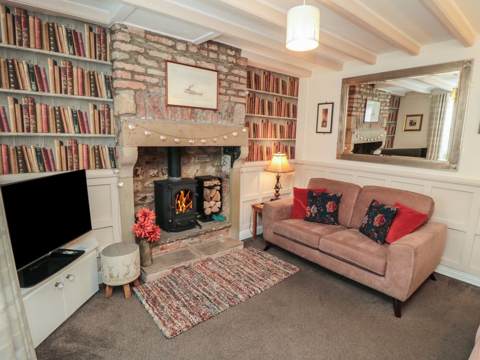 A living room with a fireplace and bookshelf at Dove Cottage in Pickering